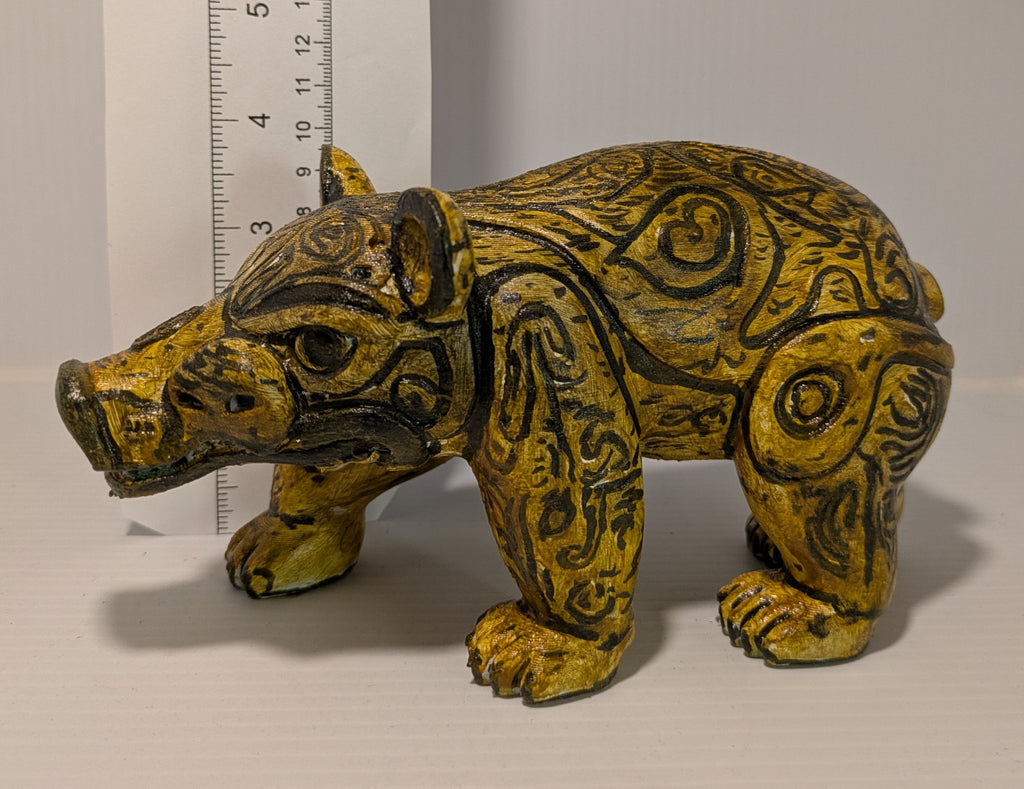 Decorative animal figurine with tribal patterns next to a ruler on a light background