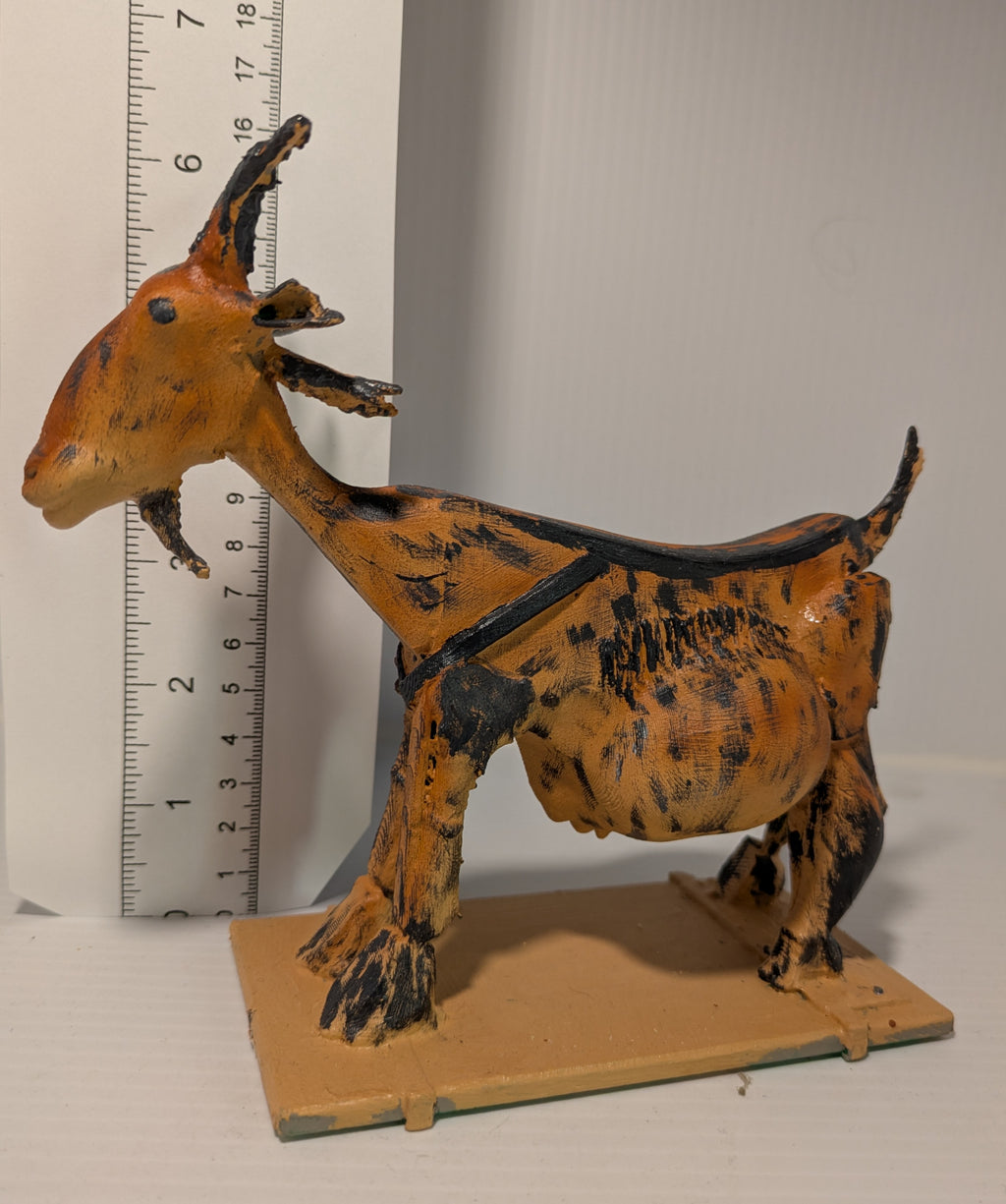 Model of a goat on a stand with a ruler for scale