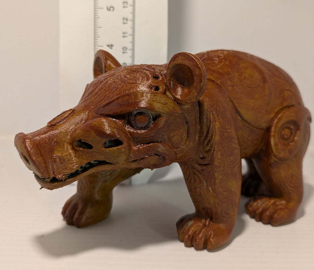 Wooden figurine of a bear with a ruler for scale on a white background